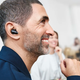 A person wearing the Sennheiser Conversation Clear Plus wireless earbuds in a crowded room.